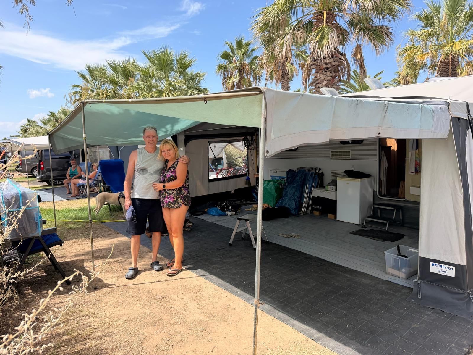 Couple standing in front of their caravan awning