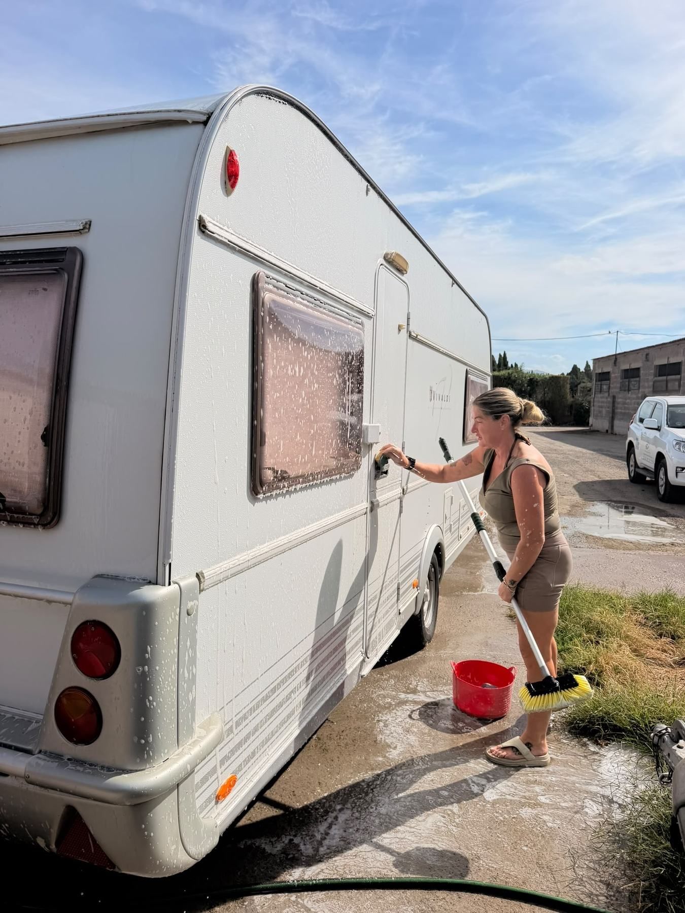 Team member scrubbing the side of a caravan with a long brush